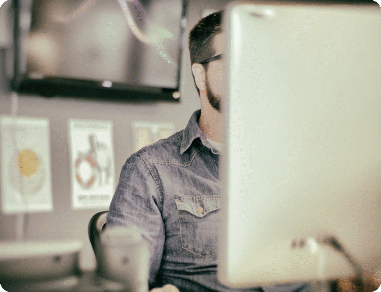 Utvikler som arbeider foran dataskjerm, symbol for teknisk fokus og løsninger innen detaljhandel.